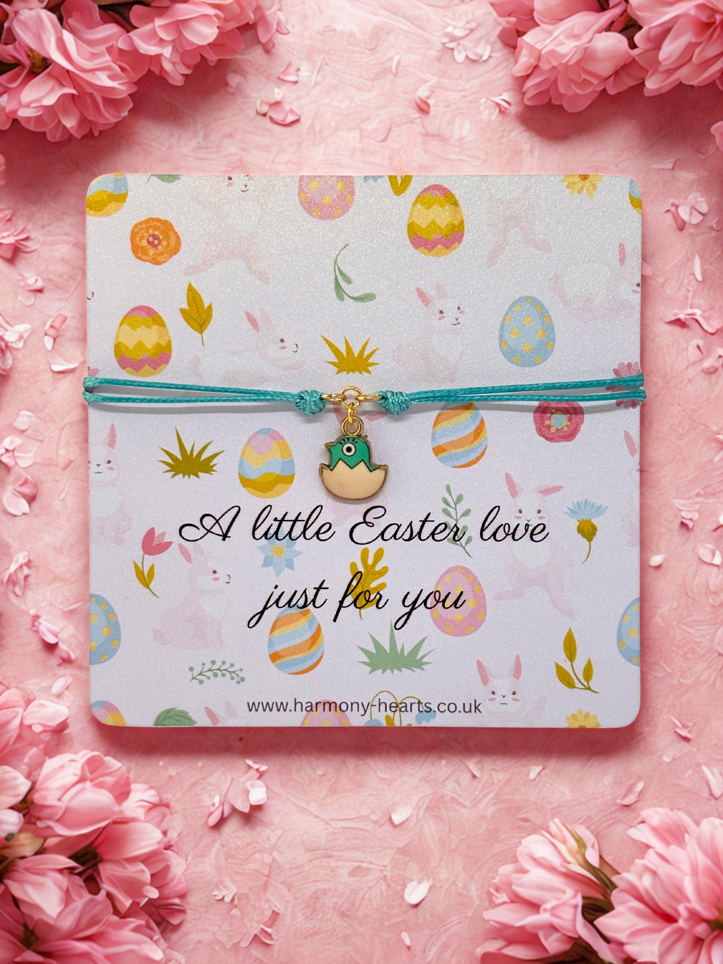 Card with Easter-themed design and an easter chick charm bracelet on a pink floral background