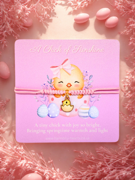 Pink Easter card with a chick illustration and text with a chick charm bracelet on a pink floral background 