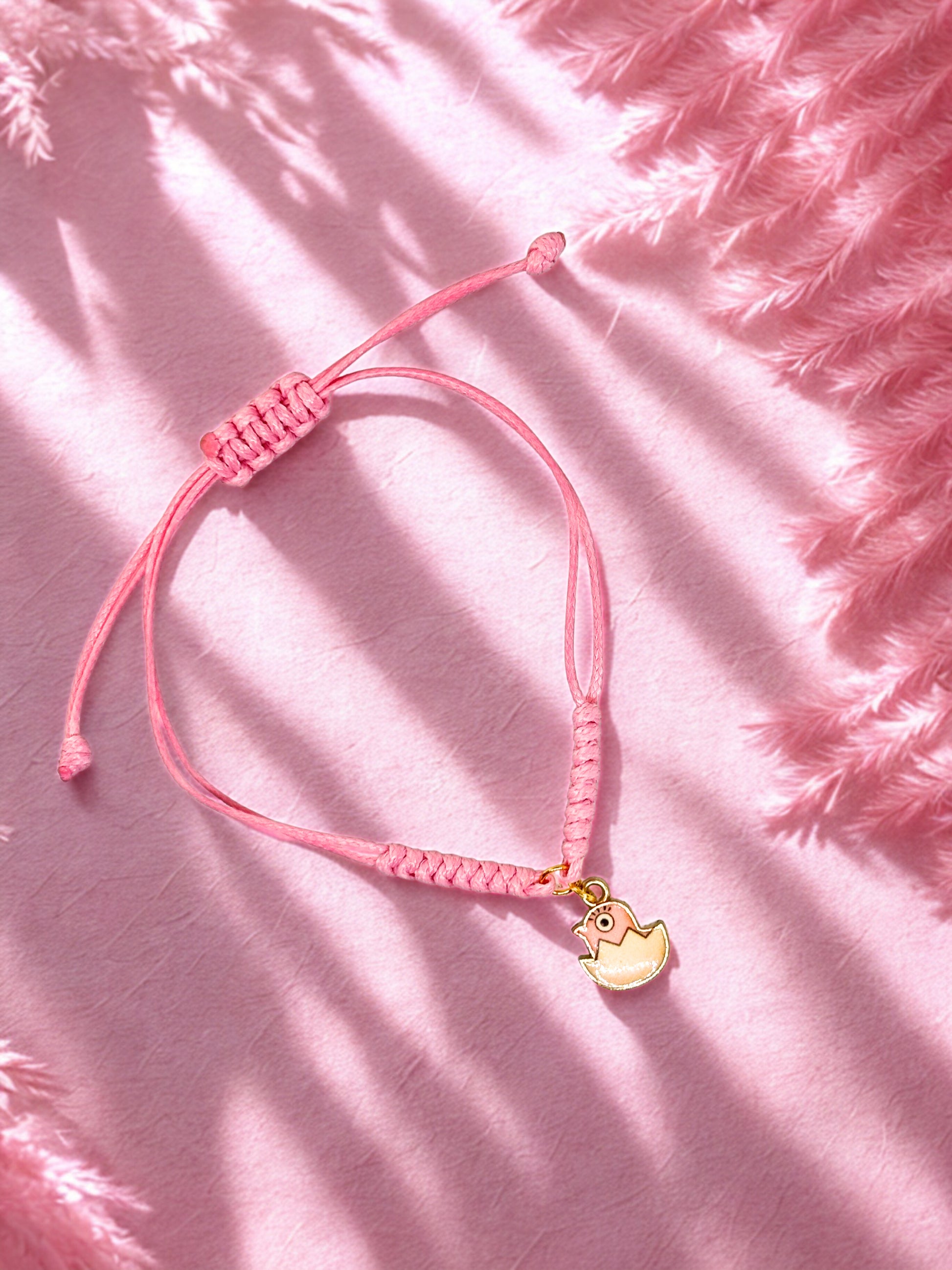 Pink bracelet with a pink chick charm on a pink textured background