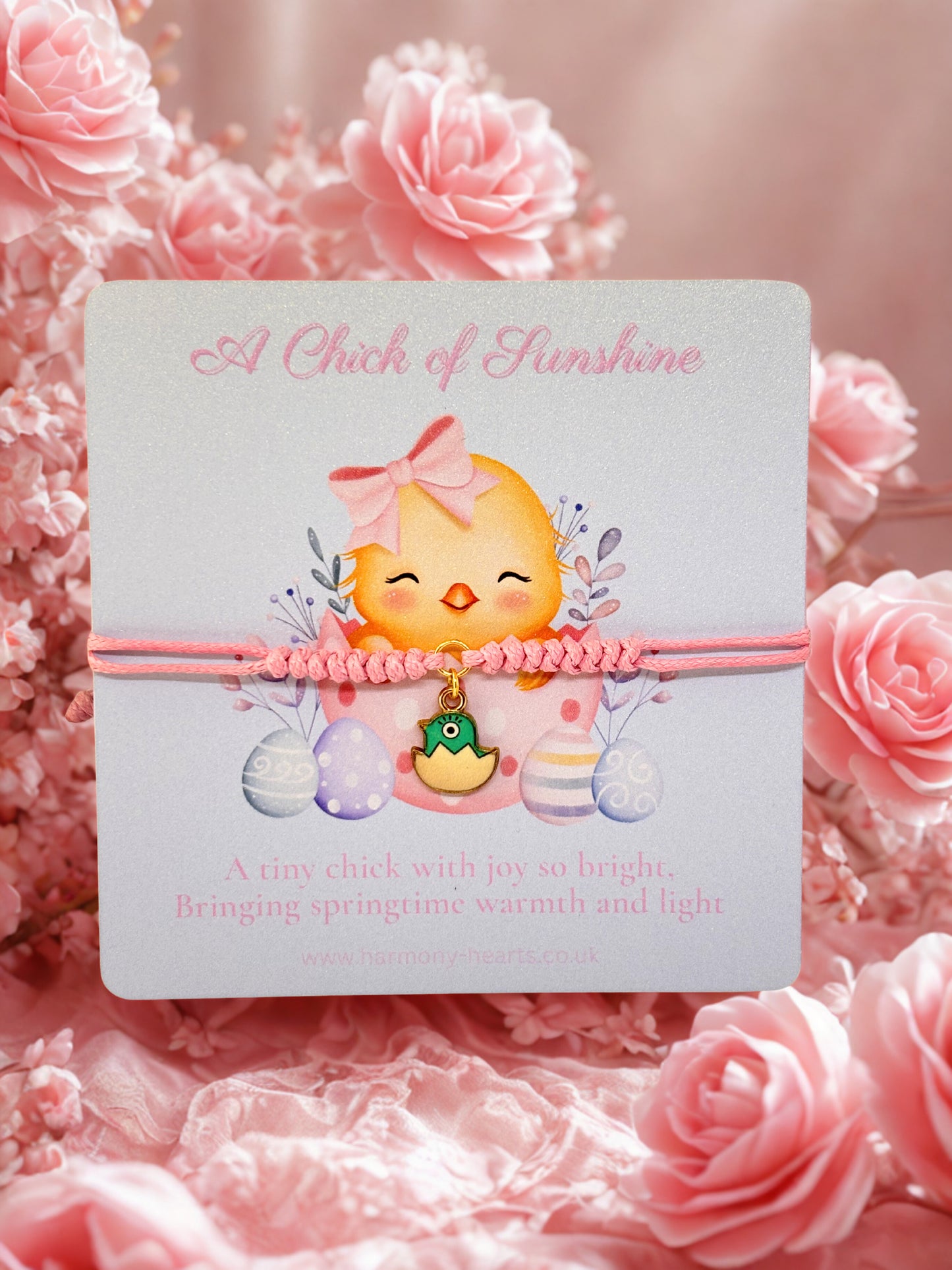 Pink cord bracelet with a chick charm presented on a branded Harmony Hearts Easter design card on a pink floral background