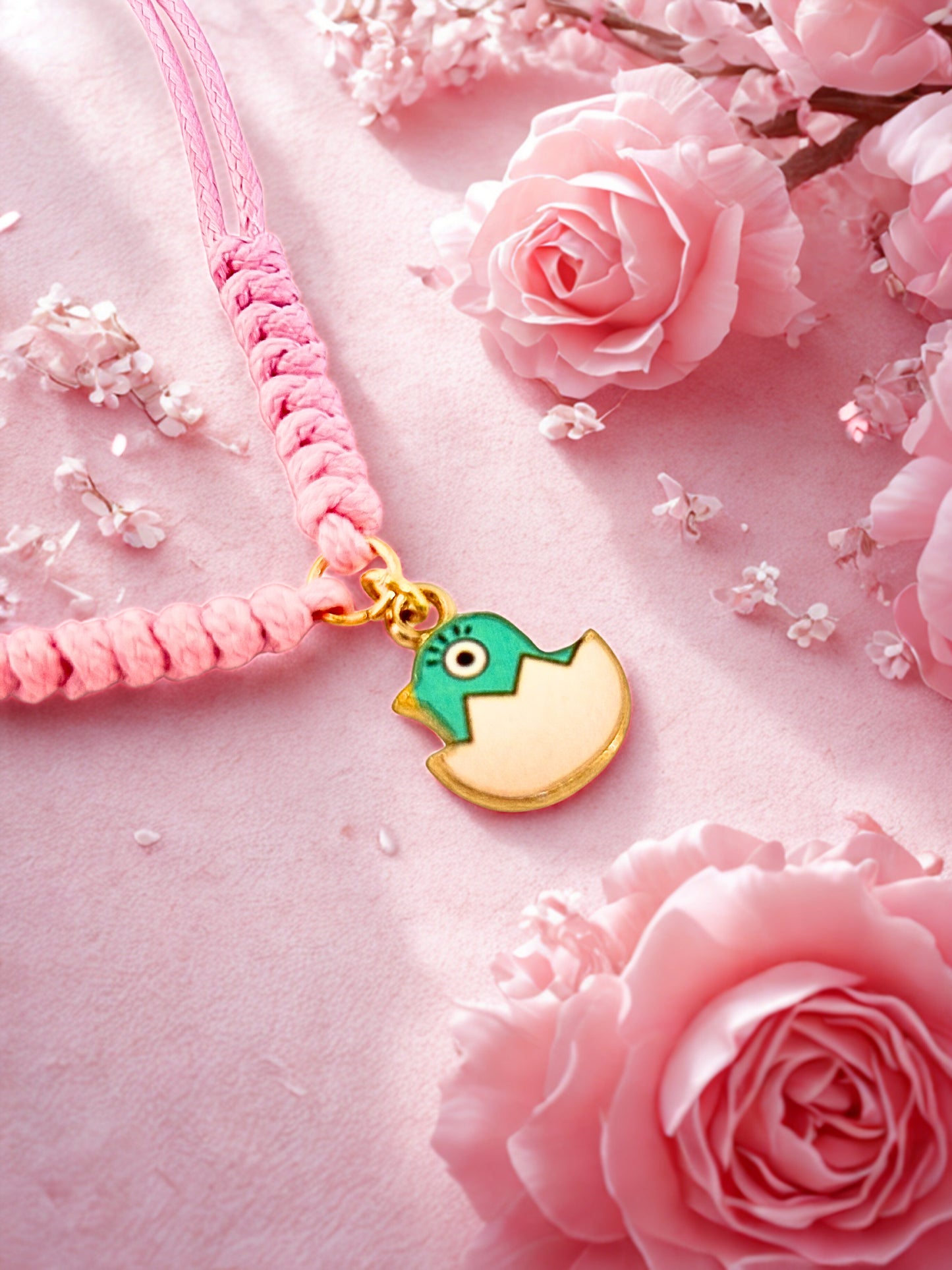 Pink cord bracelet with a green and gold Easter chick on a pink floral background