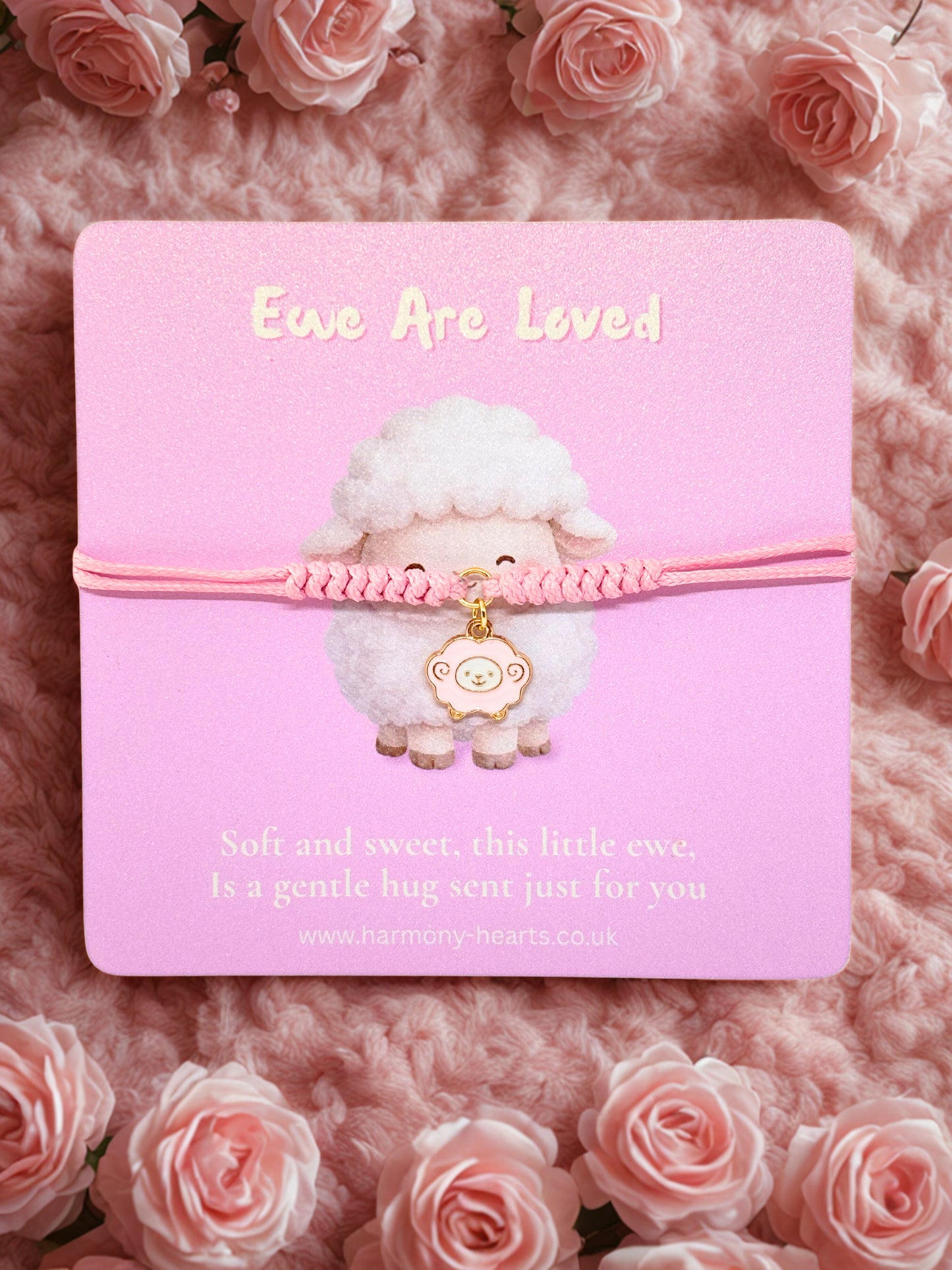 Pink cord bracelet with a sheep charm on a branded Harmony Hearts card on a pink background