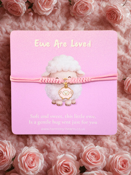 Pink cord bracelet with a sheep charm on a branded Harmony Hearts card on a pink background