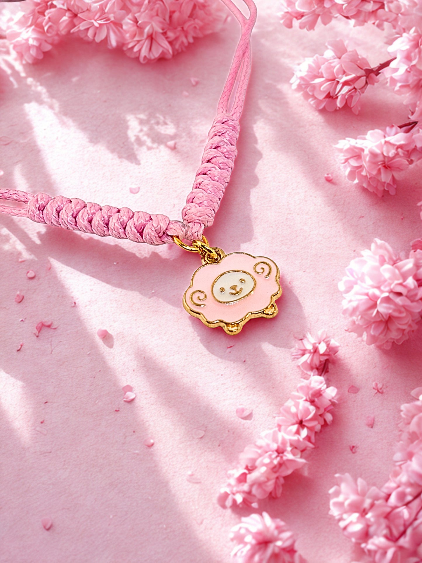 Pink cord bracelet with a pink sheep charm on a pink background