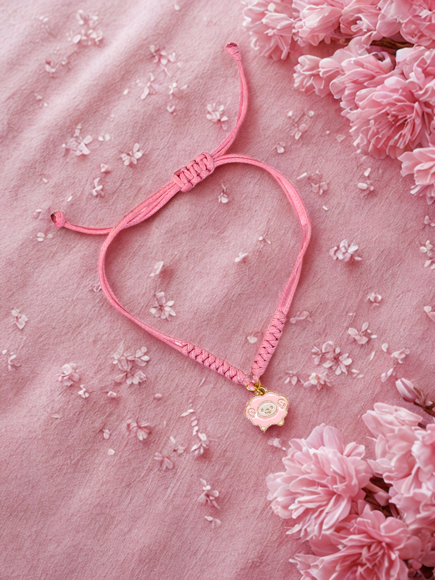 Pink cord bracelet with a pink sheep charm on a pink background
