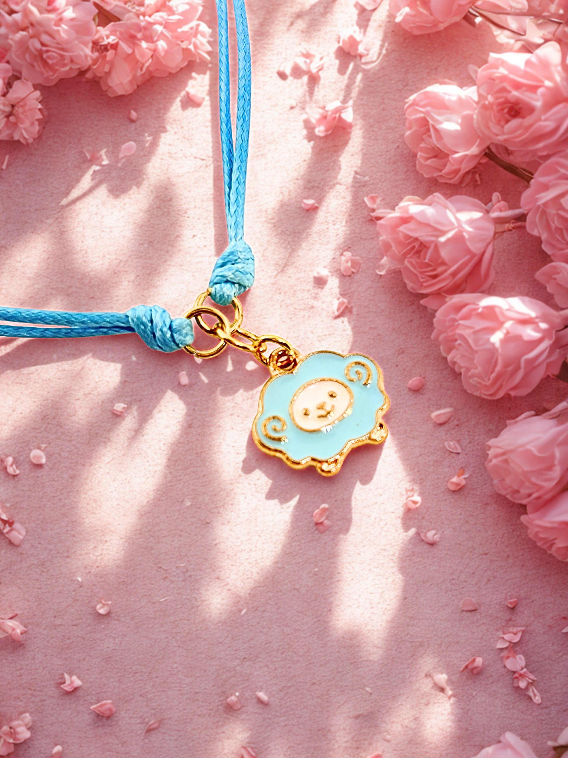 Blue cord bracelet with a sheep charm on a pink floral background