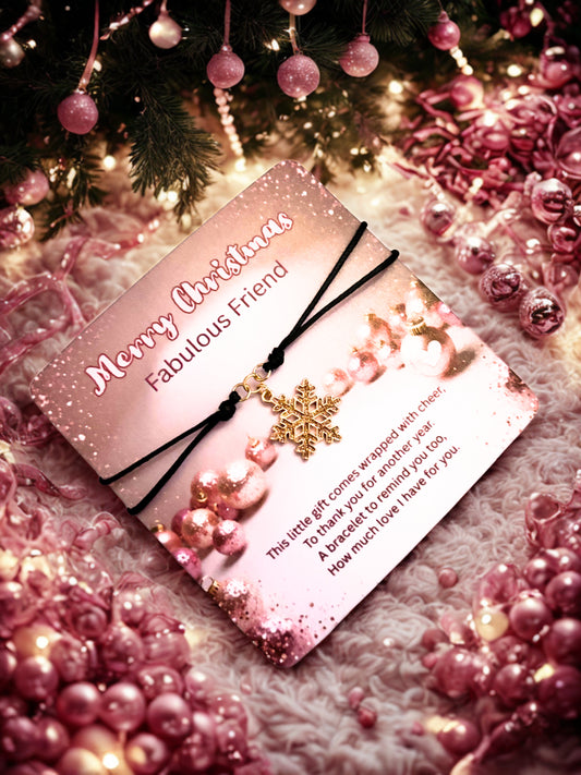 Pink Christmas card with decorative elements and a gold snowflake bracelet on a festive background