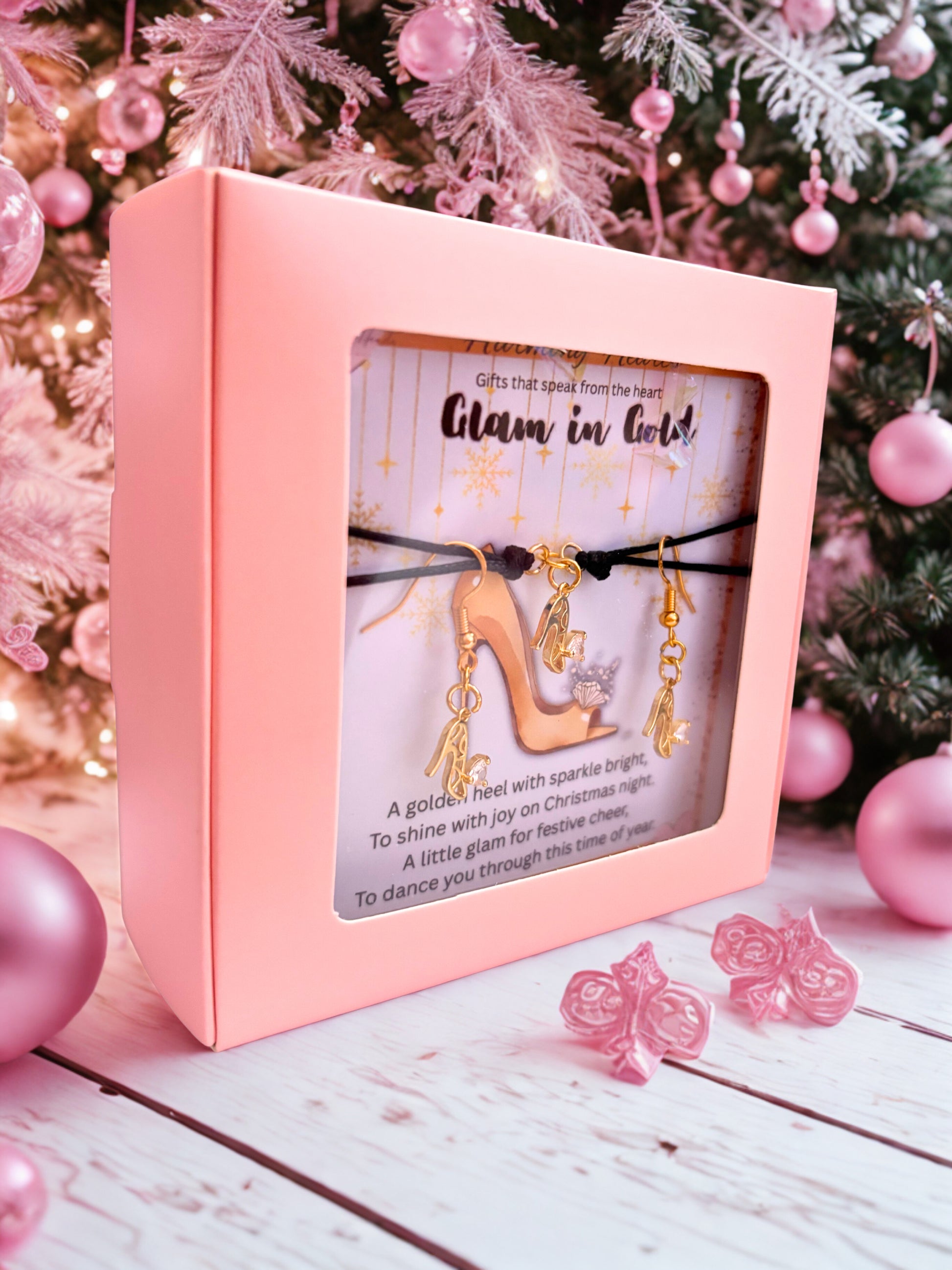 Pink box with bracelet and earrings under a Christmas tree and pink ornaments in the background
