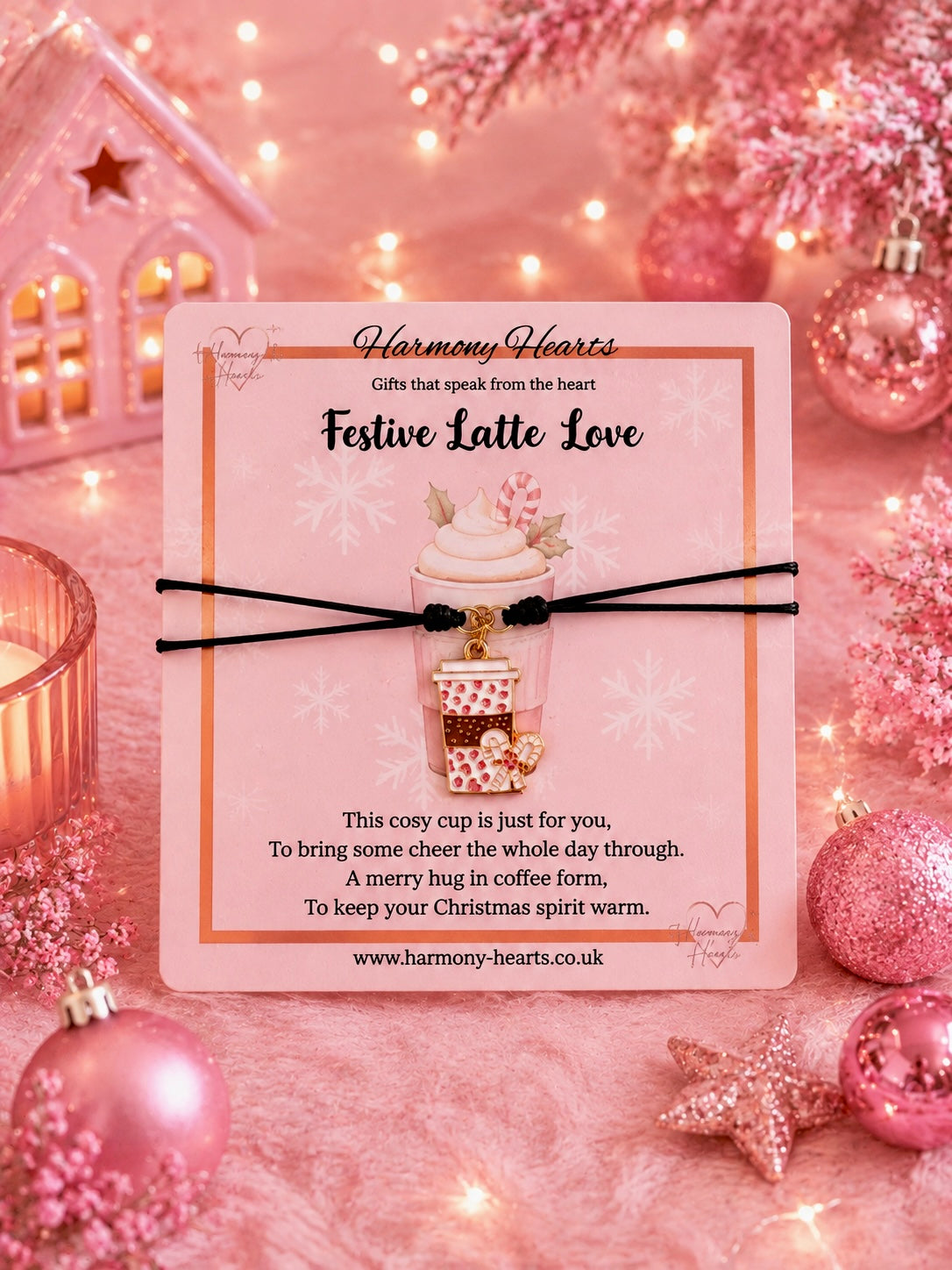 A pink card gift featuring a cord charm bracelet with a coffee cup charm and heart design. The card reads 'Festive Latte Love' and 'Harmony Hearts'.