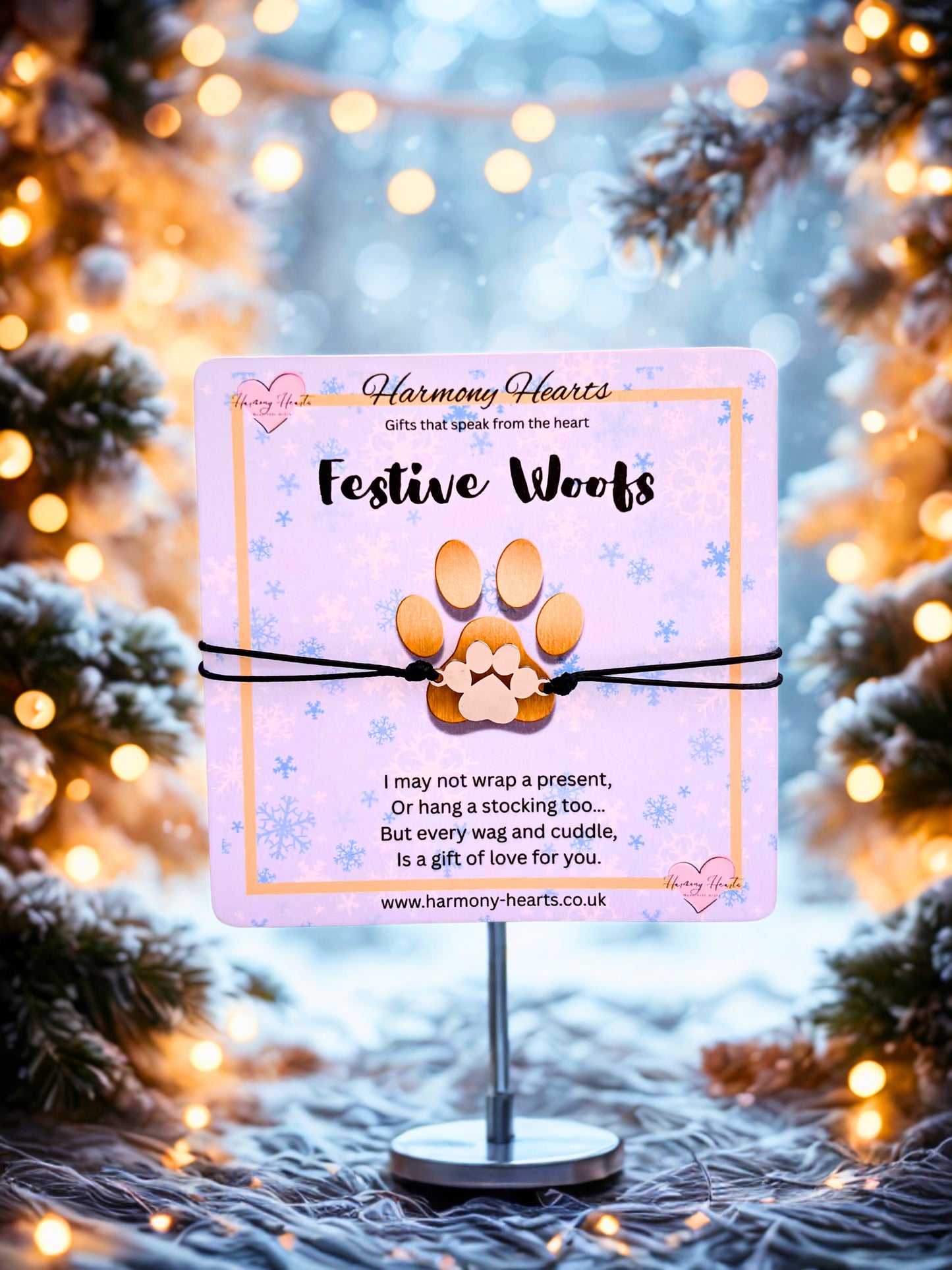 FestiveWoofs paw print bracelet on a stand with a blurred Christmas tree and lights background.