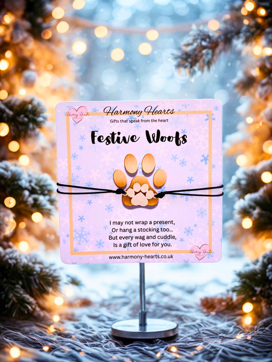 FestiveWoofs paw print bracelet on a stand with a blurred Christmas tree and lights background.
