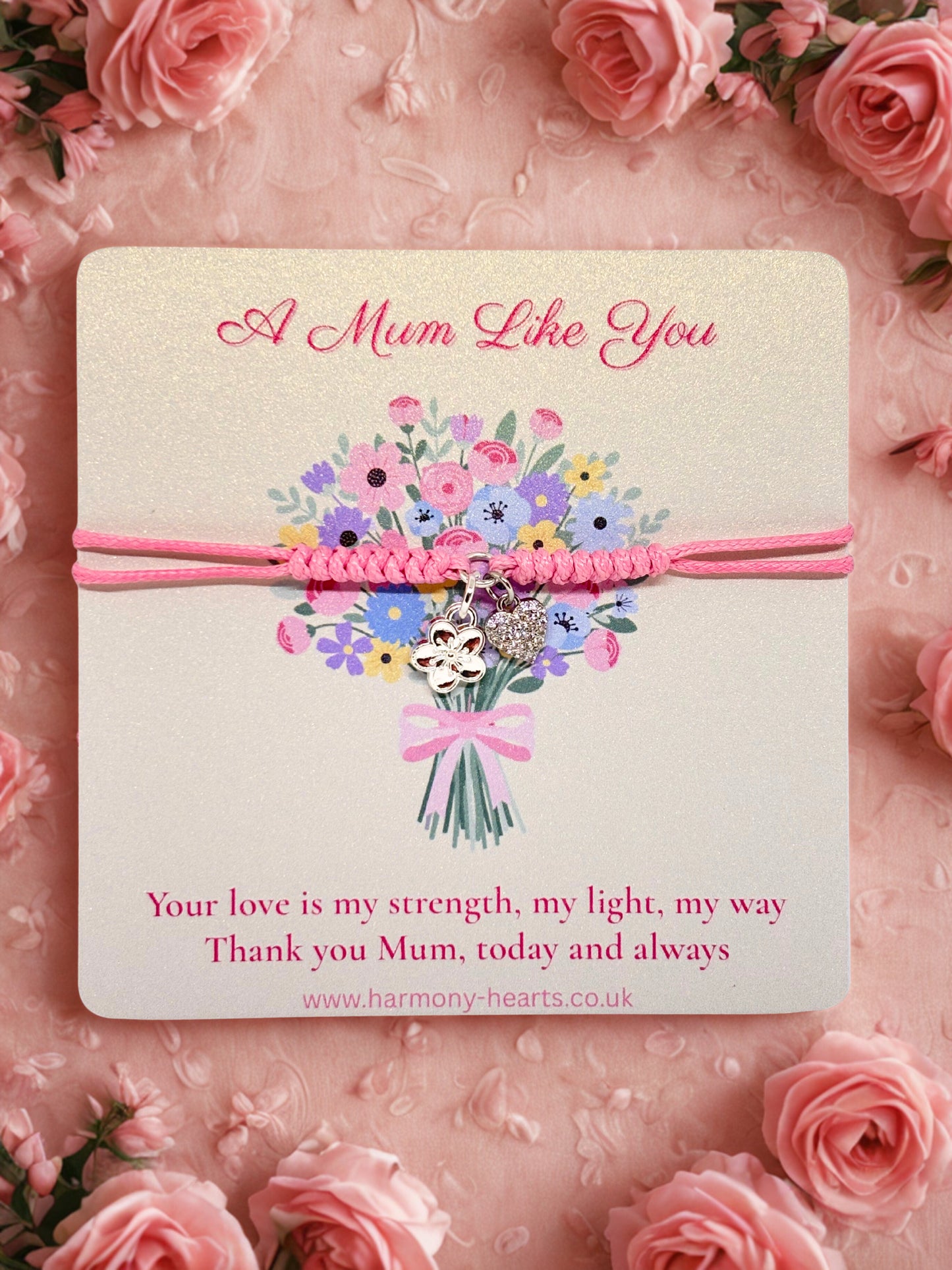 Pink cord bracelet with silver charms presented on a card with a floral design and text on a pink floral background