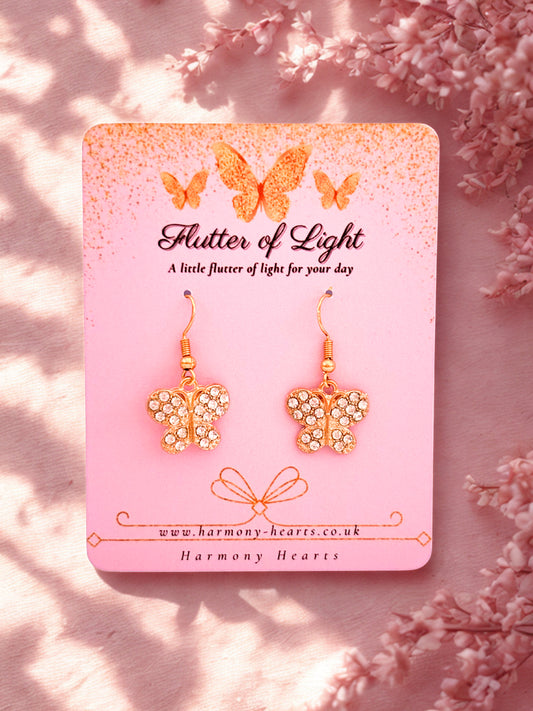 Butterfly earrings on a pink card with floral background