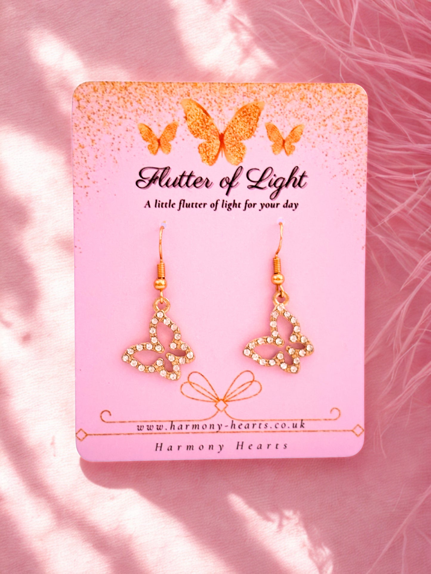 Butterfly earrings on a 'Flutter of Light' branded card with a pink background
