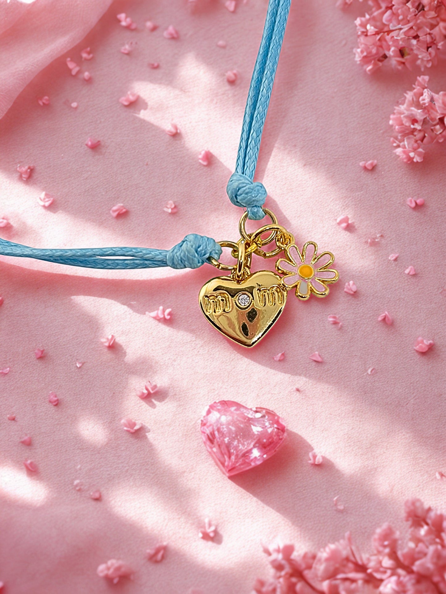 Charm bracelet with heart and flower charms on a pink background