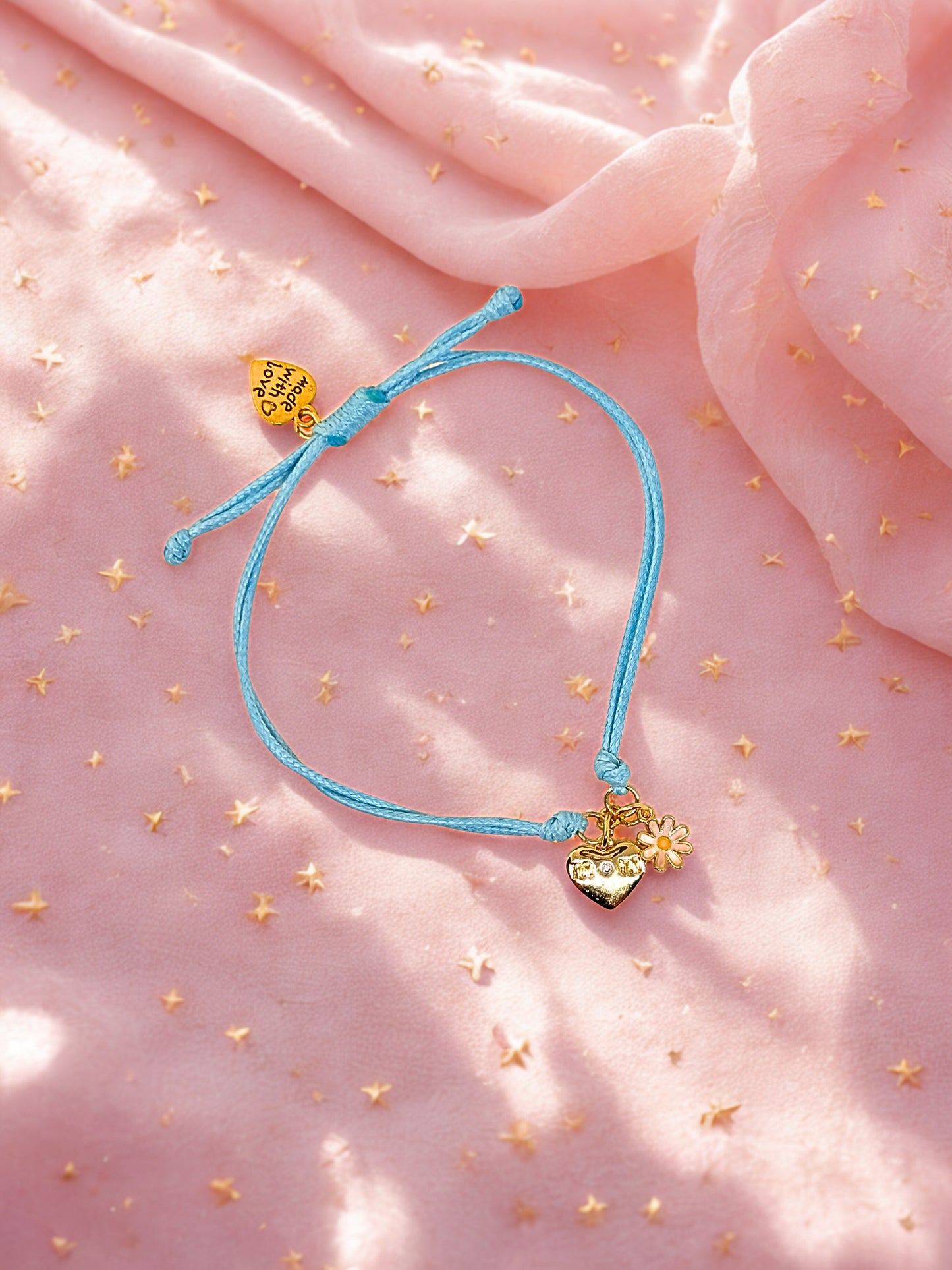 Blue bracelet with gold heart charms on a pink fabric background