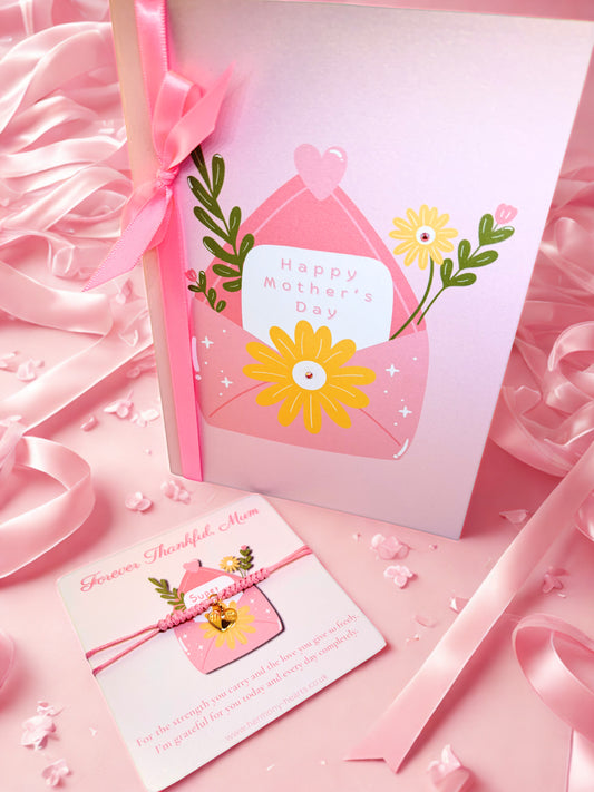 Pink Mother's Day card with flowers and ribbons on a pink background with a cord charm bracelet on a matching card