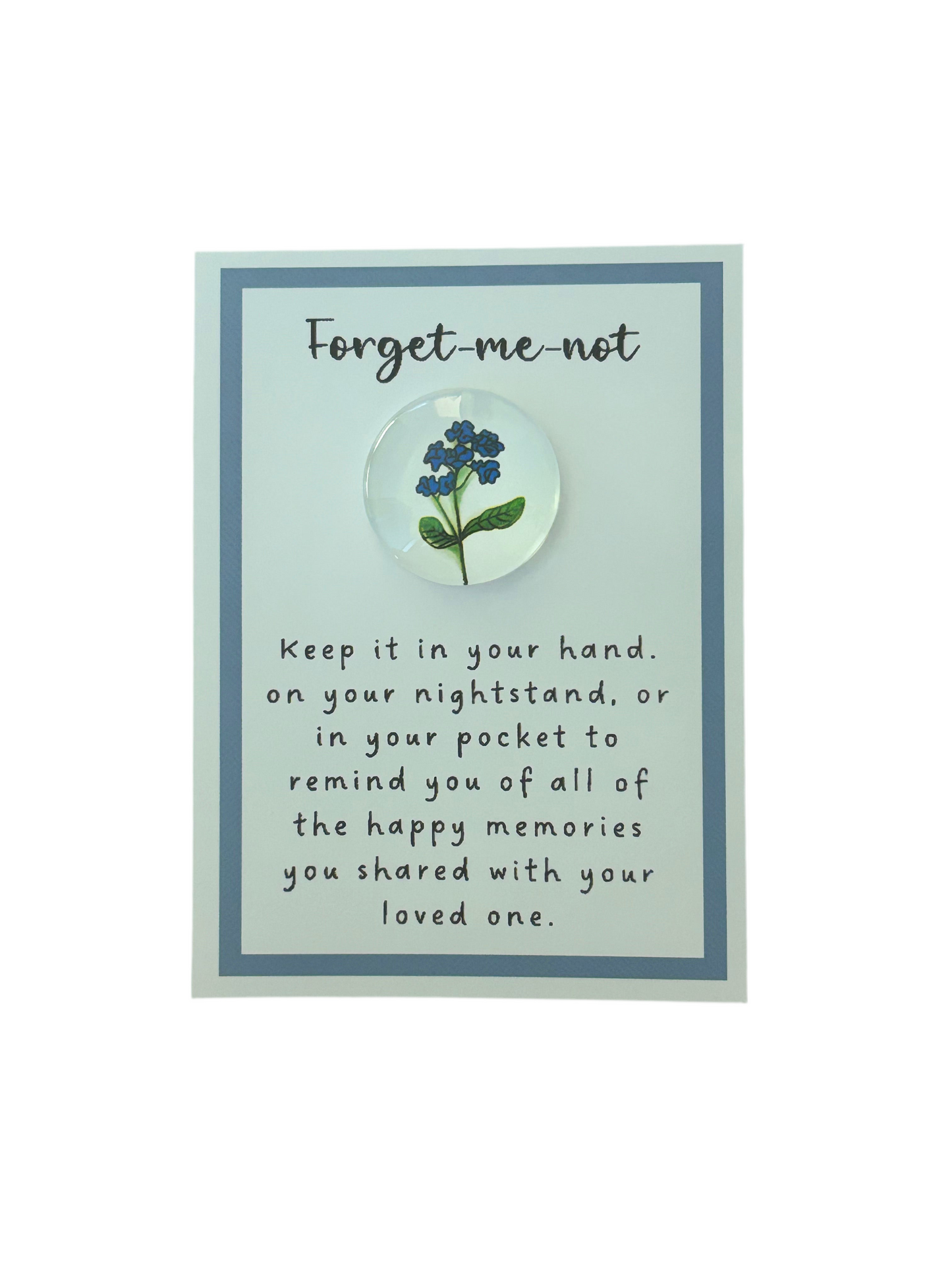 A Forget-Me-Not pocket token with a floral design, encased in a clear resin dome, displayed on a blue background with a message card.