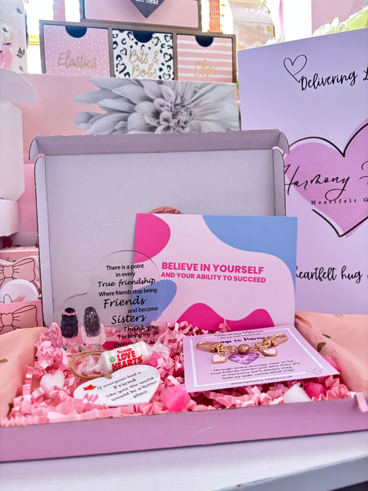 Pink gift box with jewelry and motivational card on a white surface