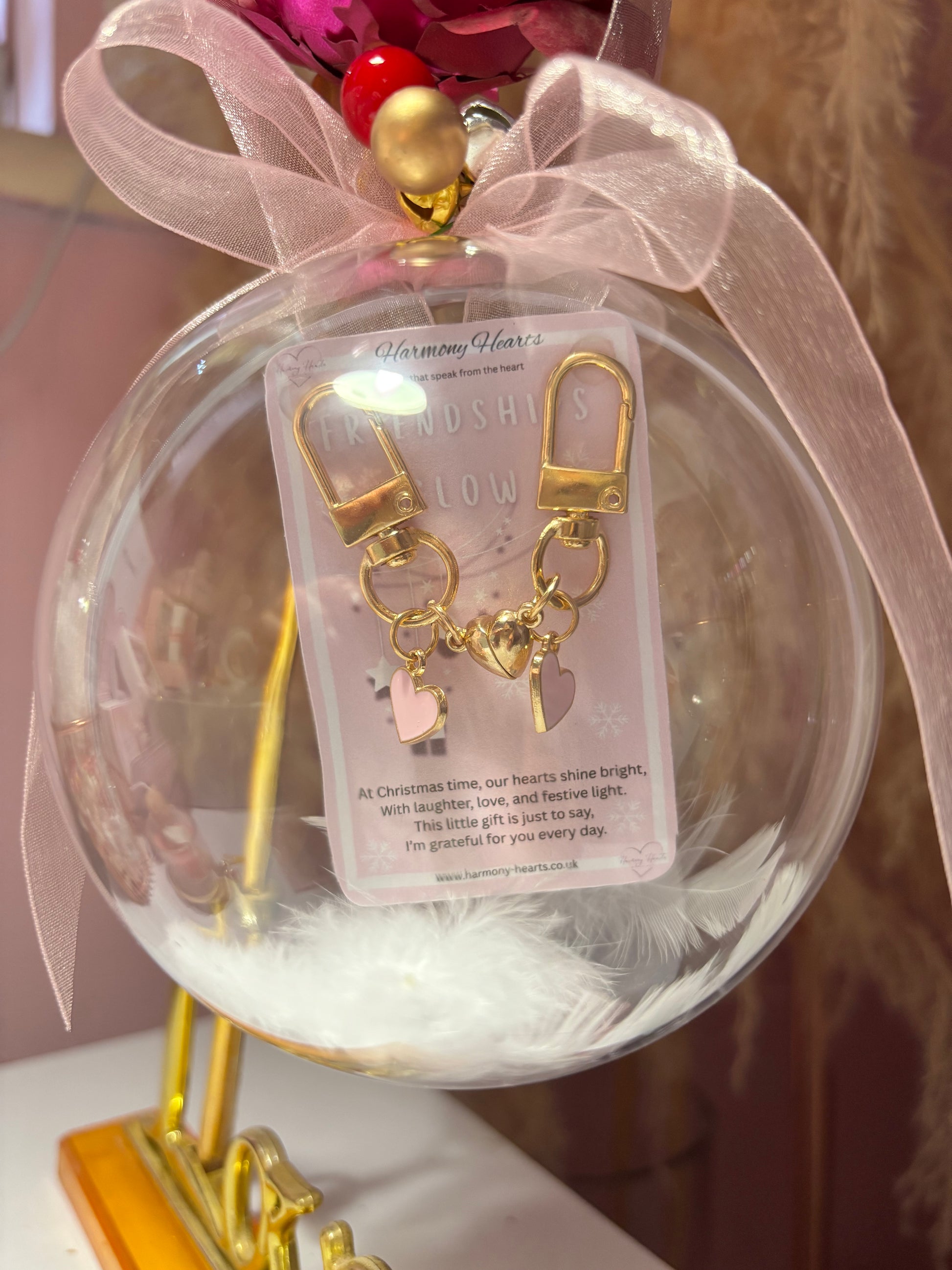 Gold keychain with heart charm in a decorative glass ball with pink ribbon