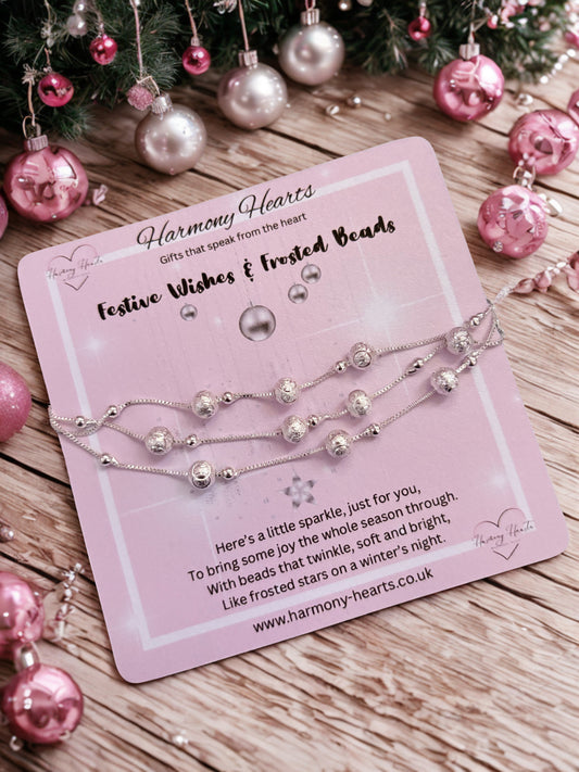 Silver beaded bracelet on a pink card with Christmas decorations in the background