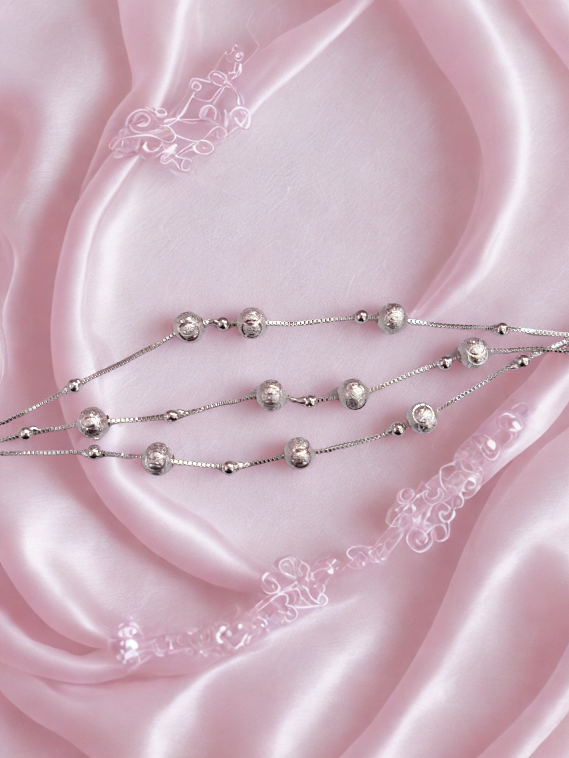 Silver beaded bracelet on pink satin fabric