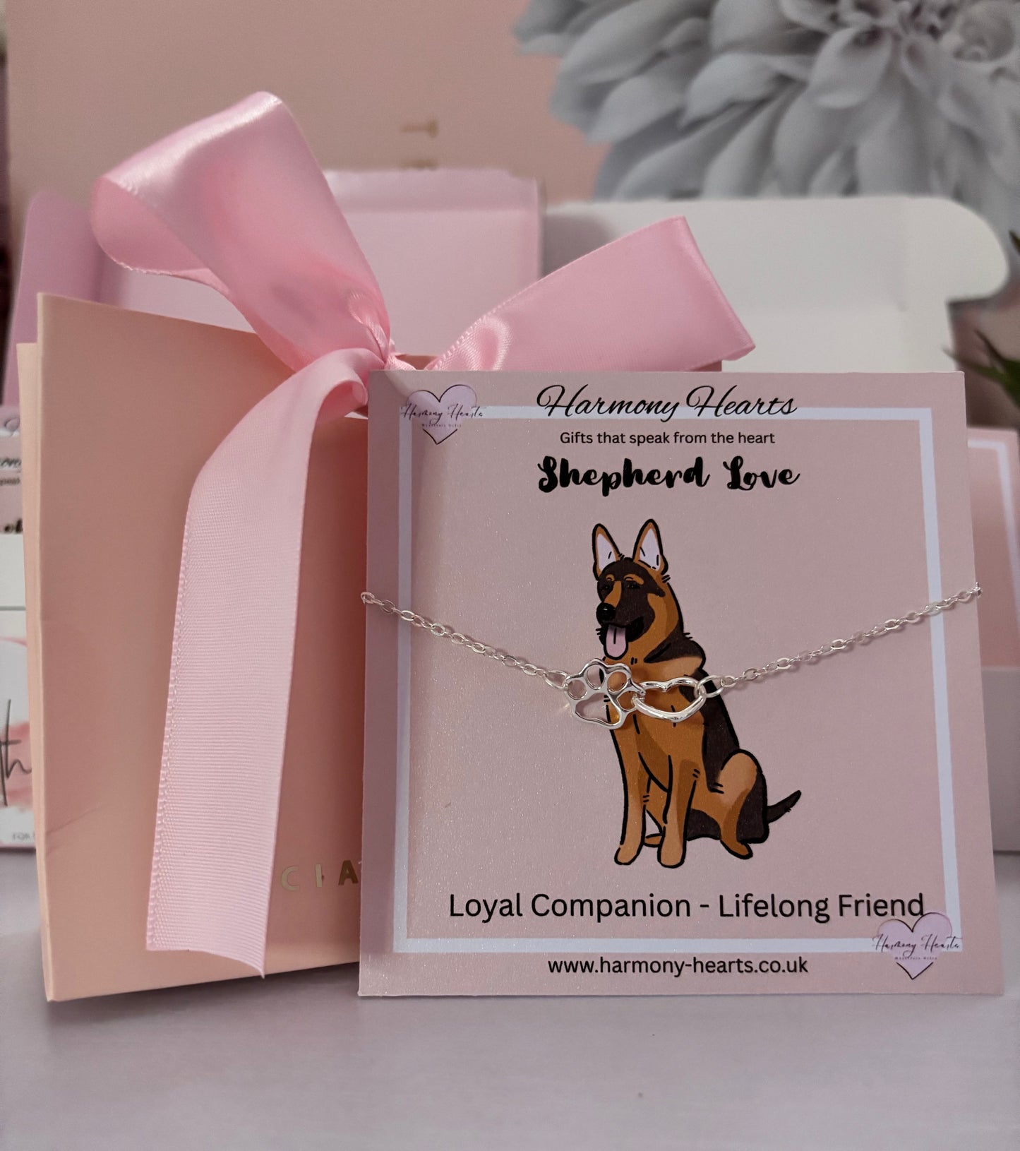 Dog-themed bracelet on a card with 'Harmony Hearts' branding, featuring a pink ribbon and gift box.