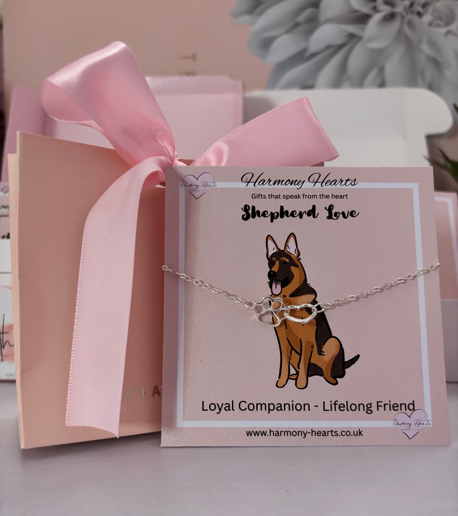 Dog-themed bracelet on a card with 'Harmony Hearts' branding, featuring a pink ribbon and gift box.