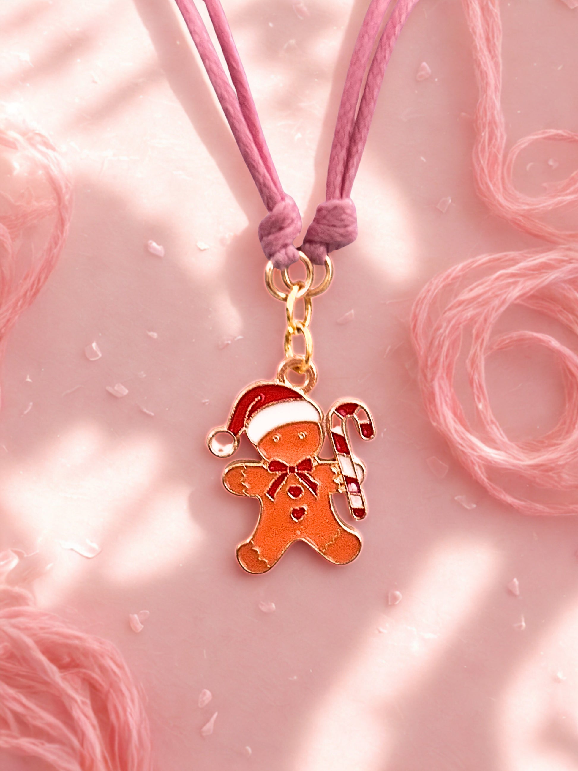Gingerbread man charm on a pink cord against a pink background