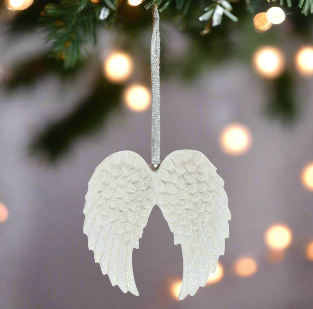 Decorative angel wings ornament hanging on a tree with blurred lights in the background