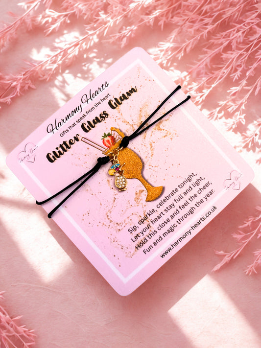 Bracelet with a gold cocktail charm on a pink card with text, against a soft pink background.