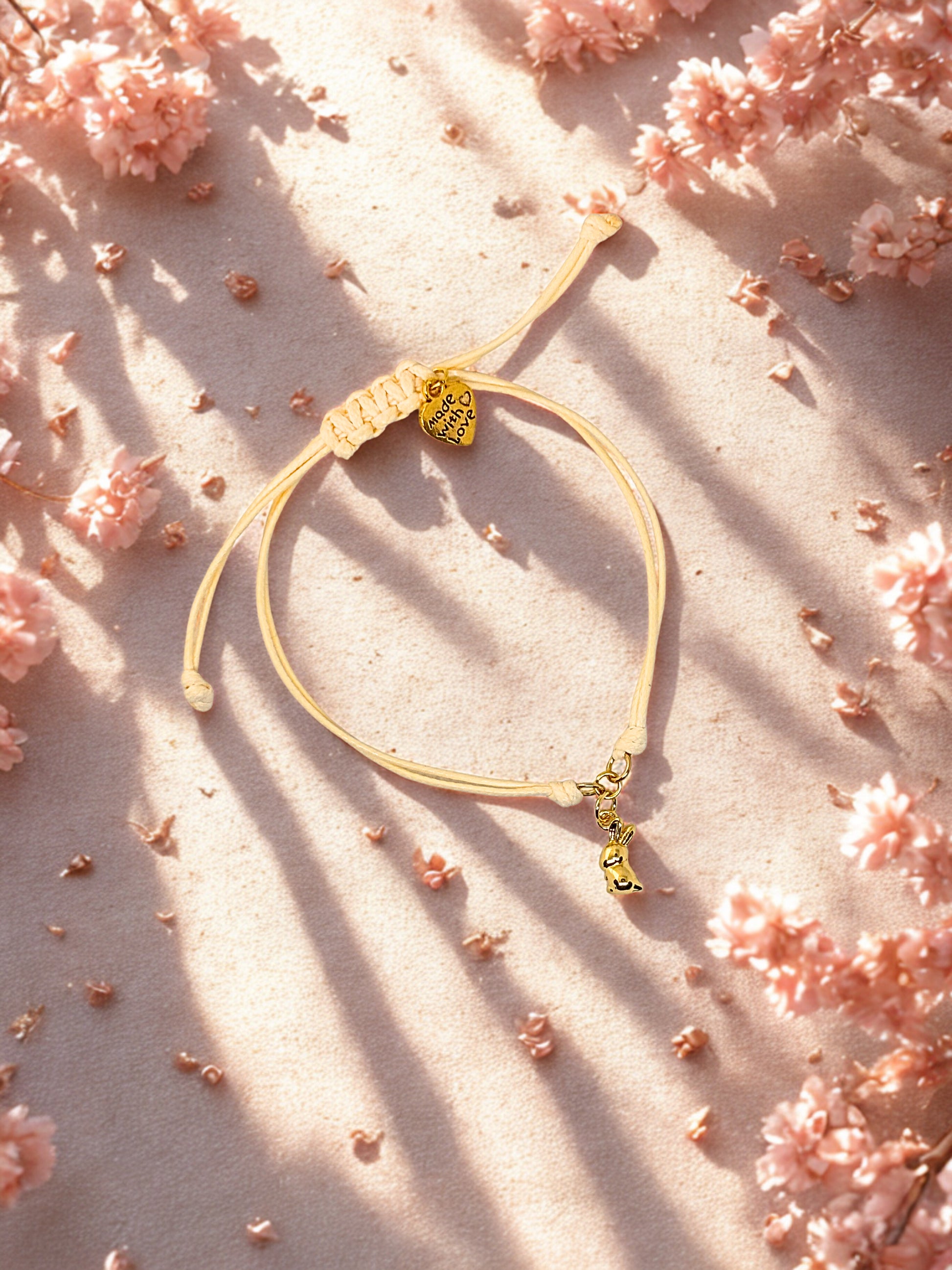 Cord bracelet with a bunny charm on a pink floral background