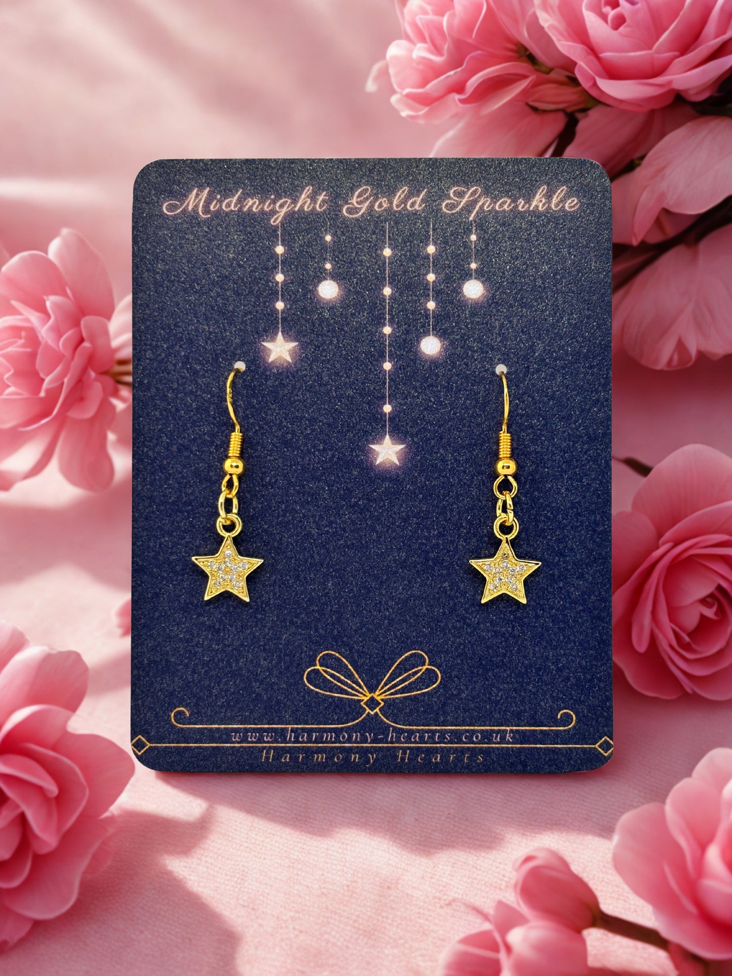 Gold star earrings on a Midnight Gold Sparkle card with pink flowers in the background