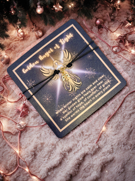 Gold angel charm on a decorative card with Christmas lights and decorations in the background
