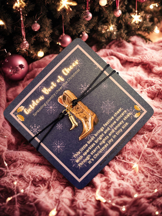 Gold boot charm on a blue card with Christmas decorations in the background