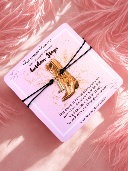 Gold boot charm on a pink card with text, against a pink fluffy background