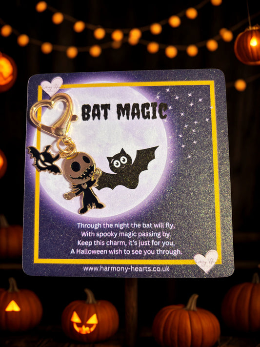 Halloween-themed keychain with bat design on a card, surrounded by pumpkins and string lights.