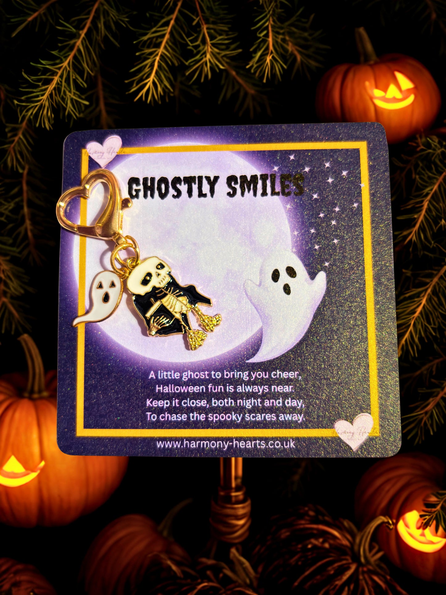 Halloween-themed keychain with ghost and skeleton design on a card with pumpkins and foliage in the background.