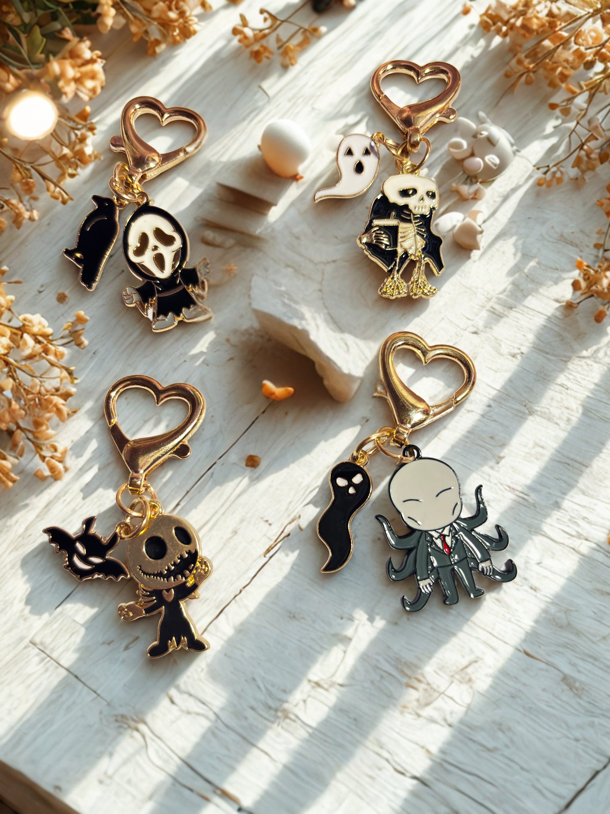 Set of skeleton-themed keychains on a light wooden surface with dried flowers.