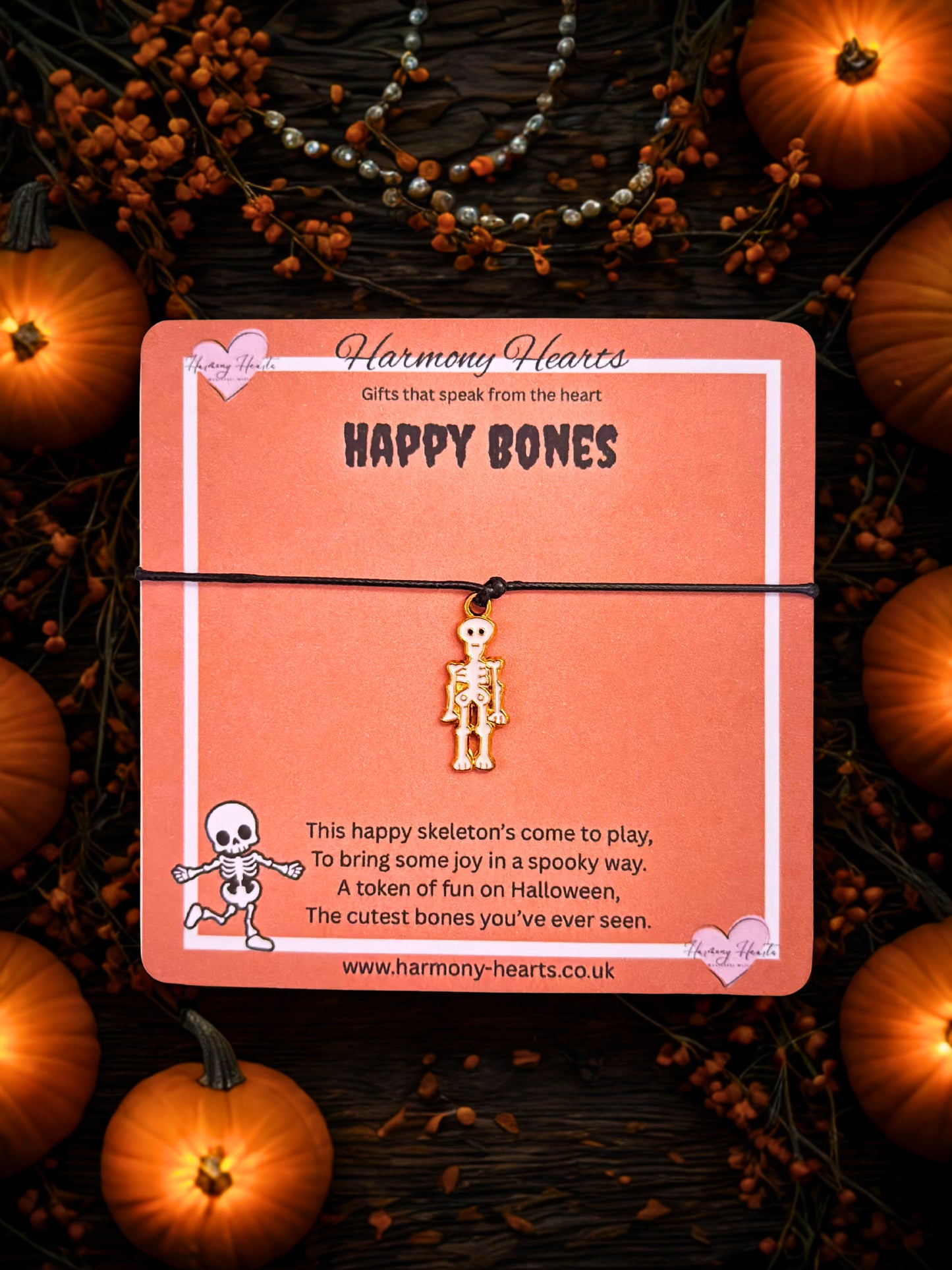 Halloween-themed product with skeleton charm on a card, surrounded by pumpkins and decorations.