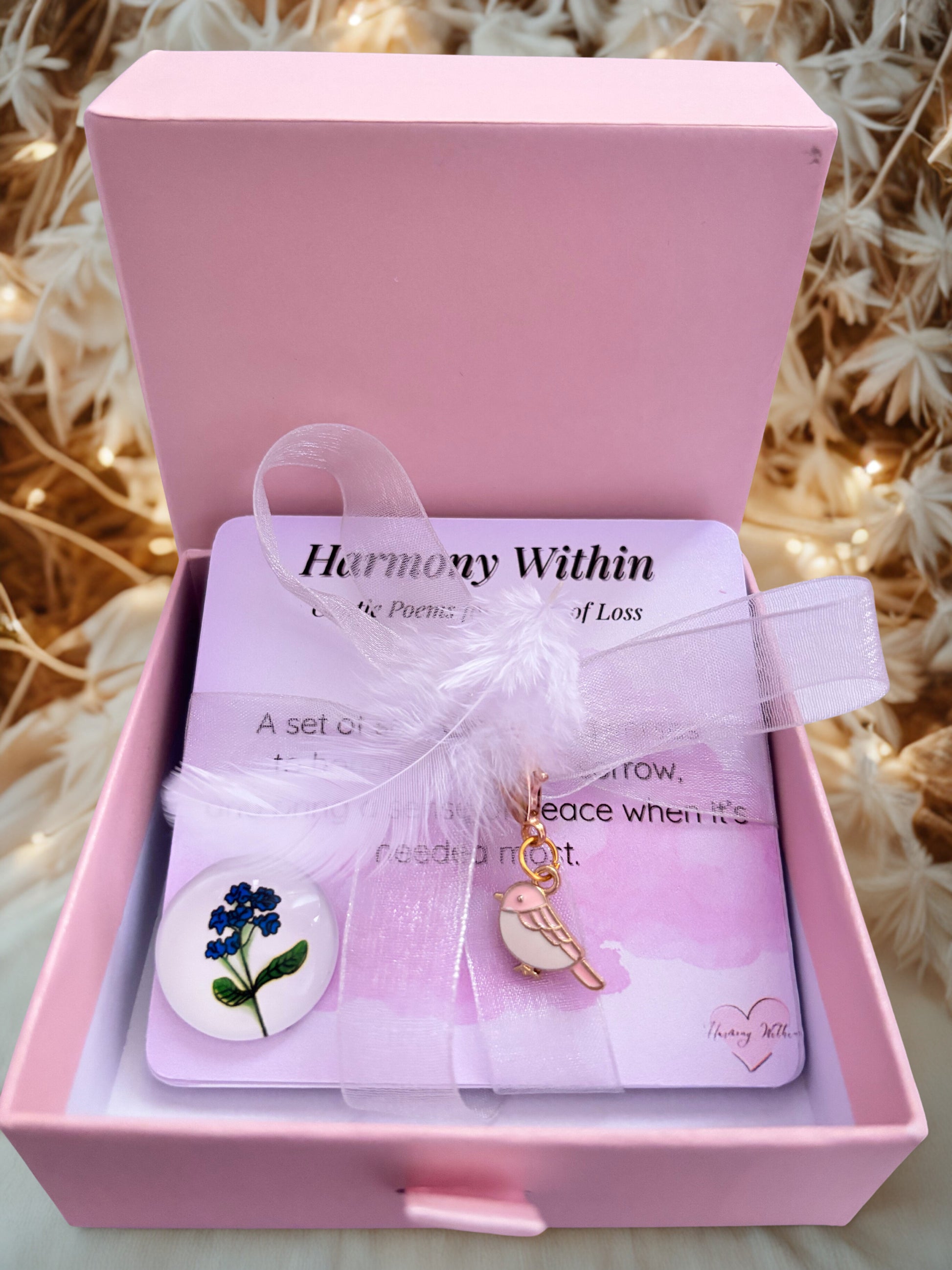 Pink jewelry box with 'Harmony Within' card and charms on a textured background