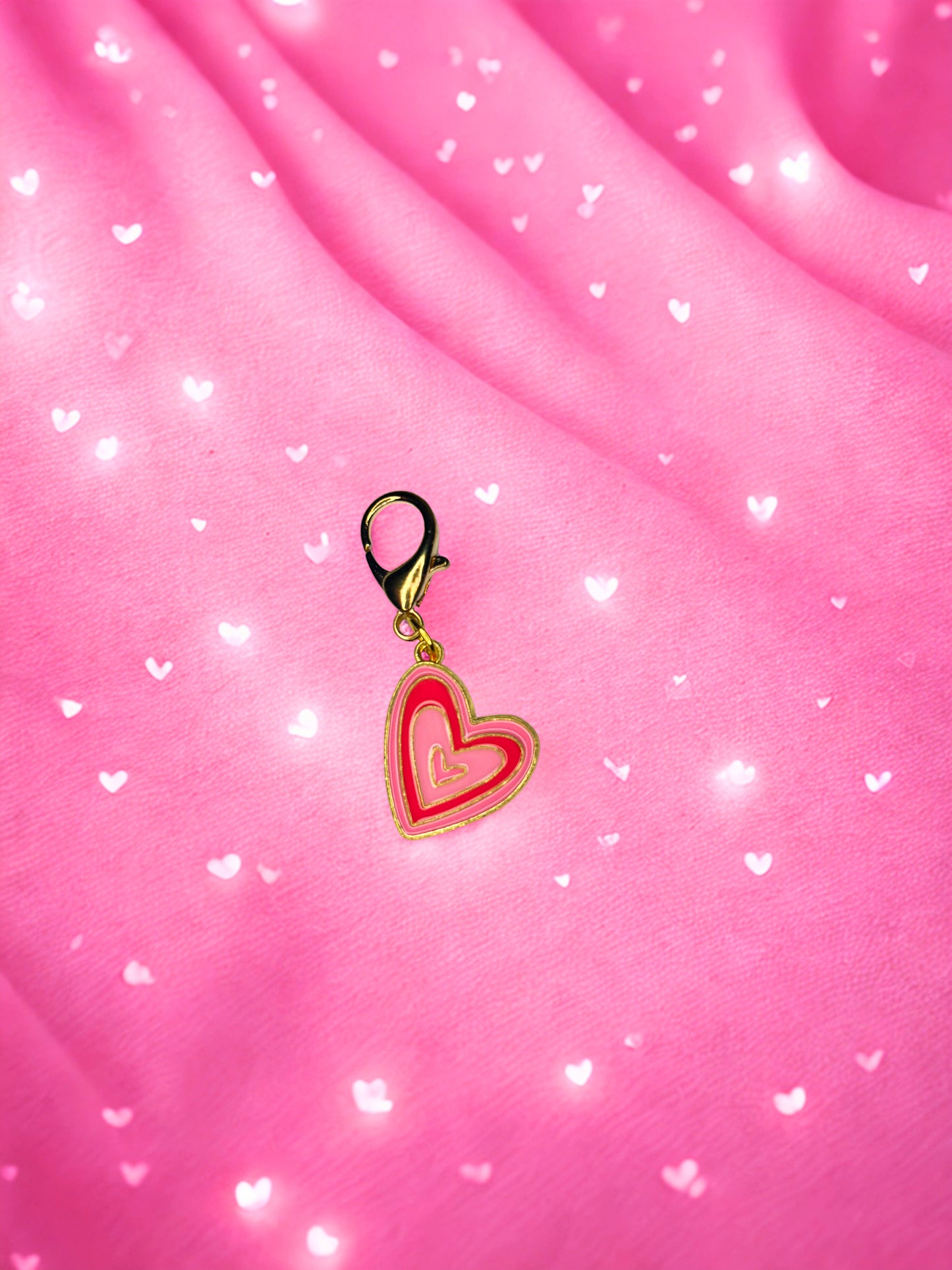Heart-shaped charm on a pink fabric background with heart patterns
