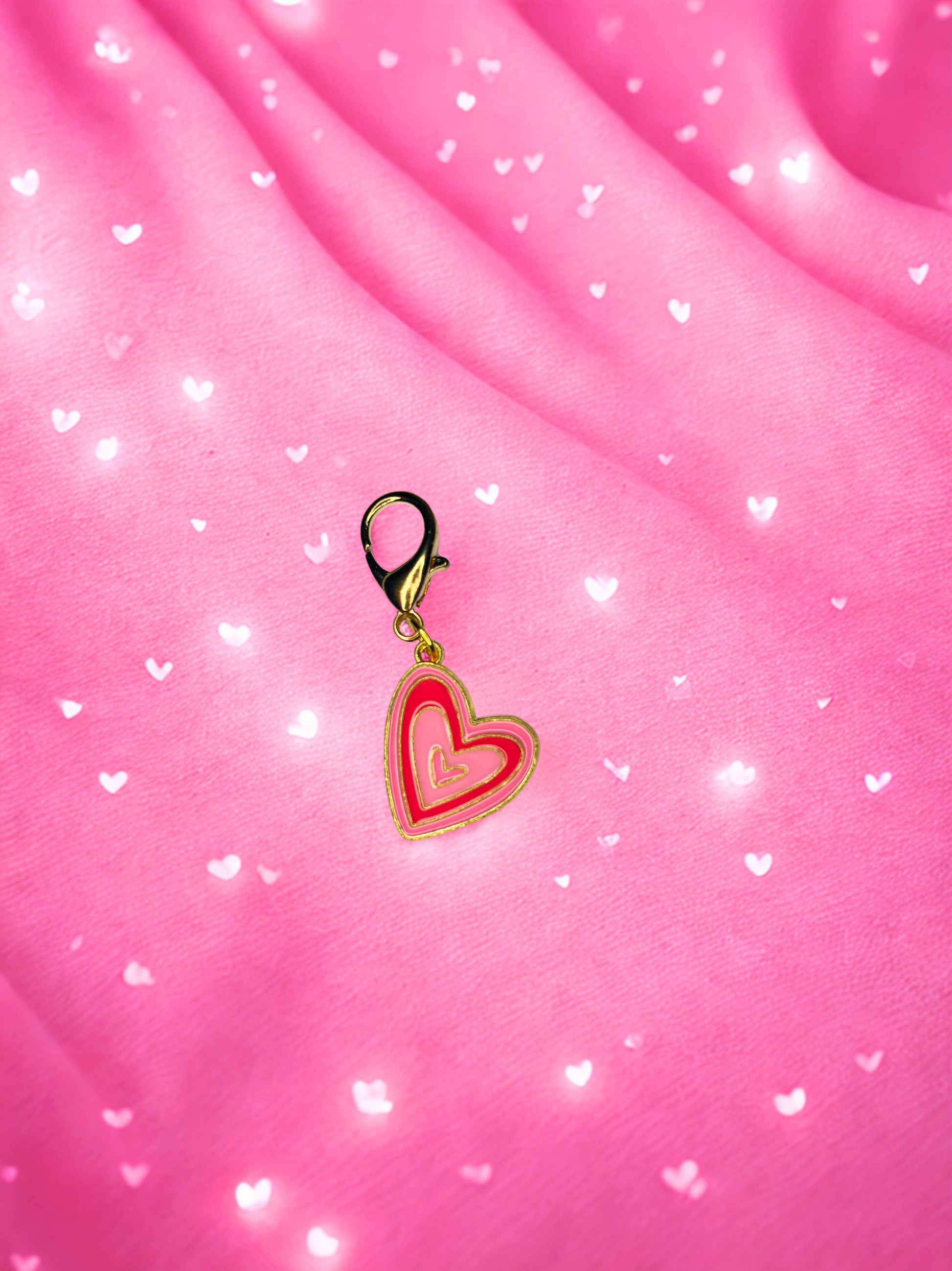 Heart-shaped charm on a pink fabric background with heart patterns