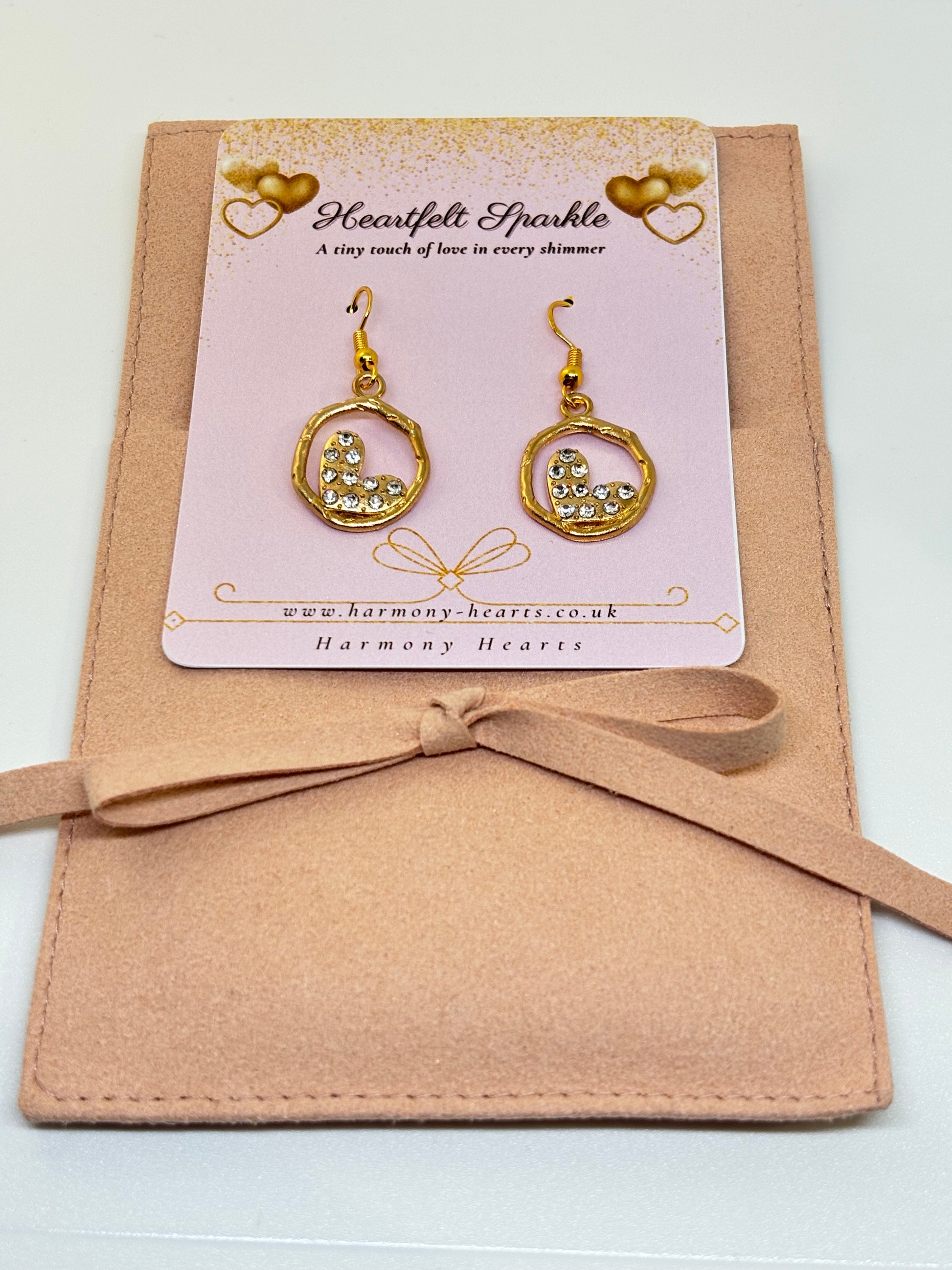Gold heart-shaped earrings on a 'Heartfelt Sparkle' card with a beige bow