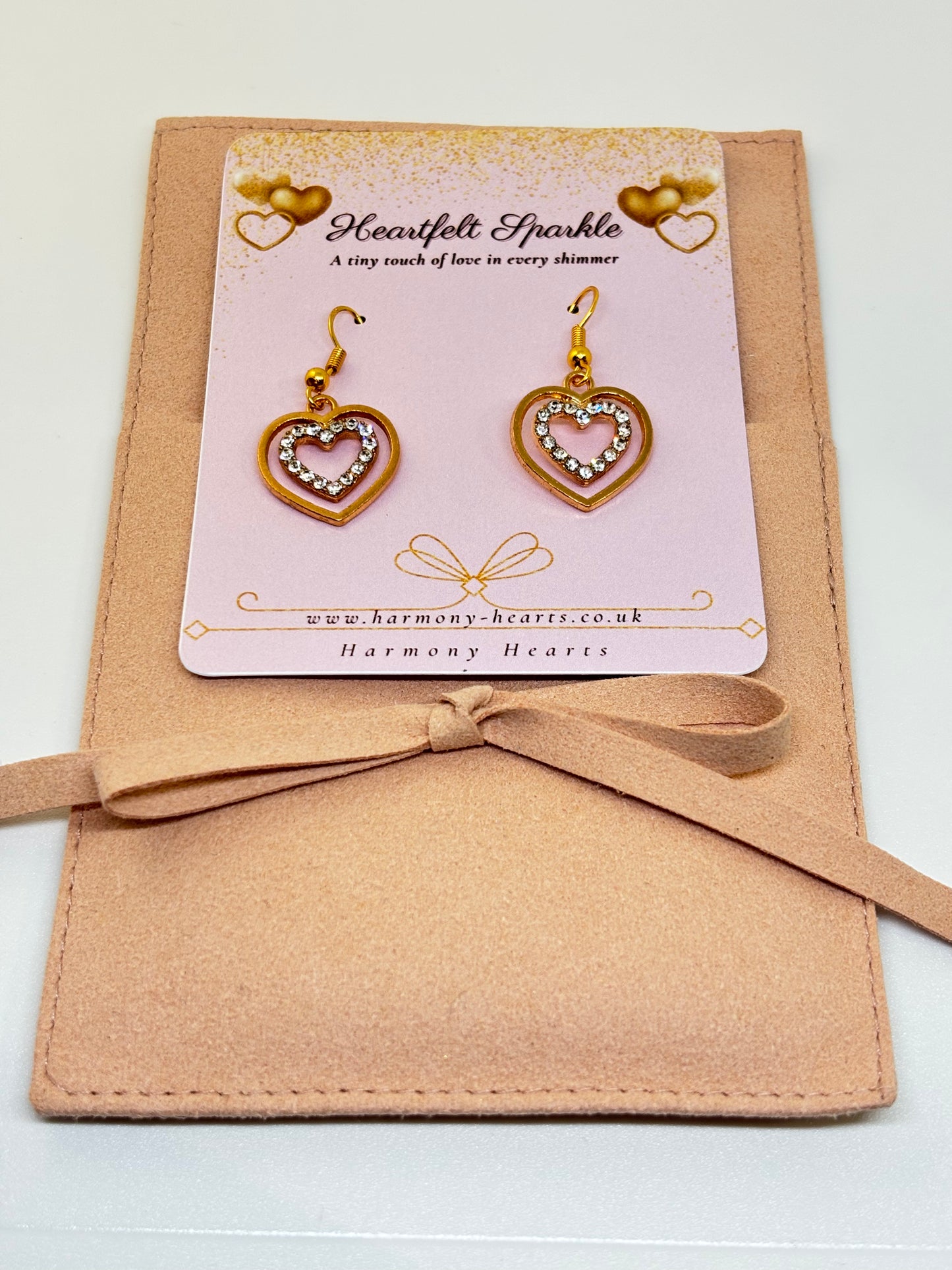 Heart-shaped earrings on a Harmony Hearts branded card with a beige ribbon
