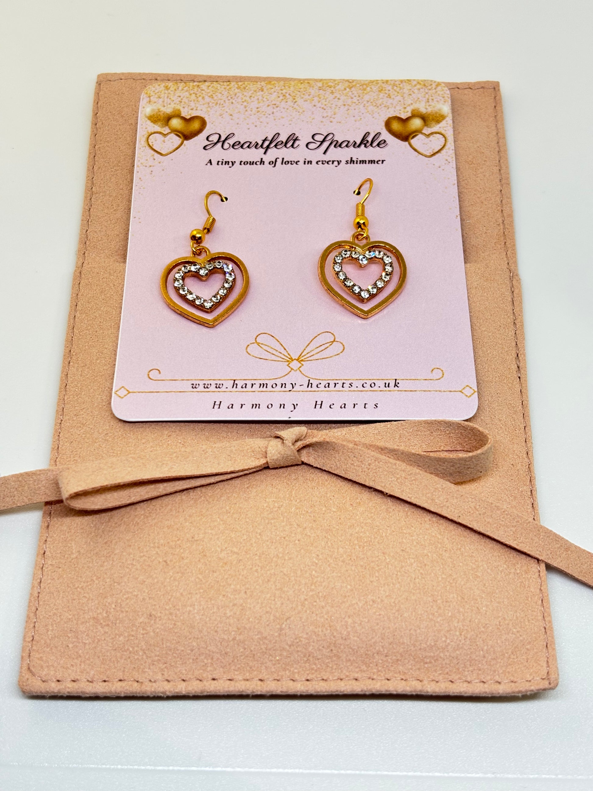 Heart-shaped earrings on a Harmony Hearts branded card with a beige ribbon