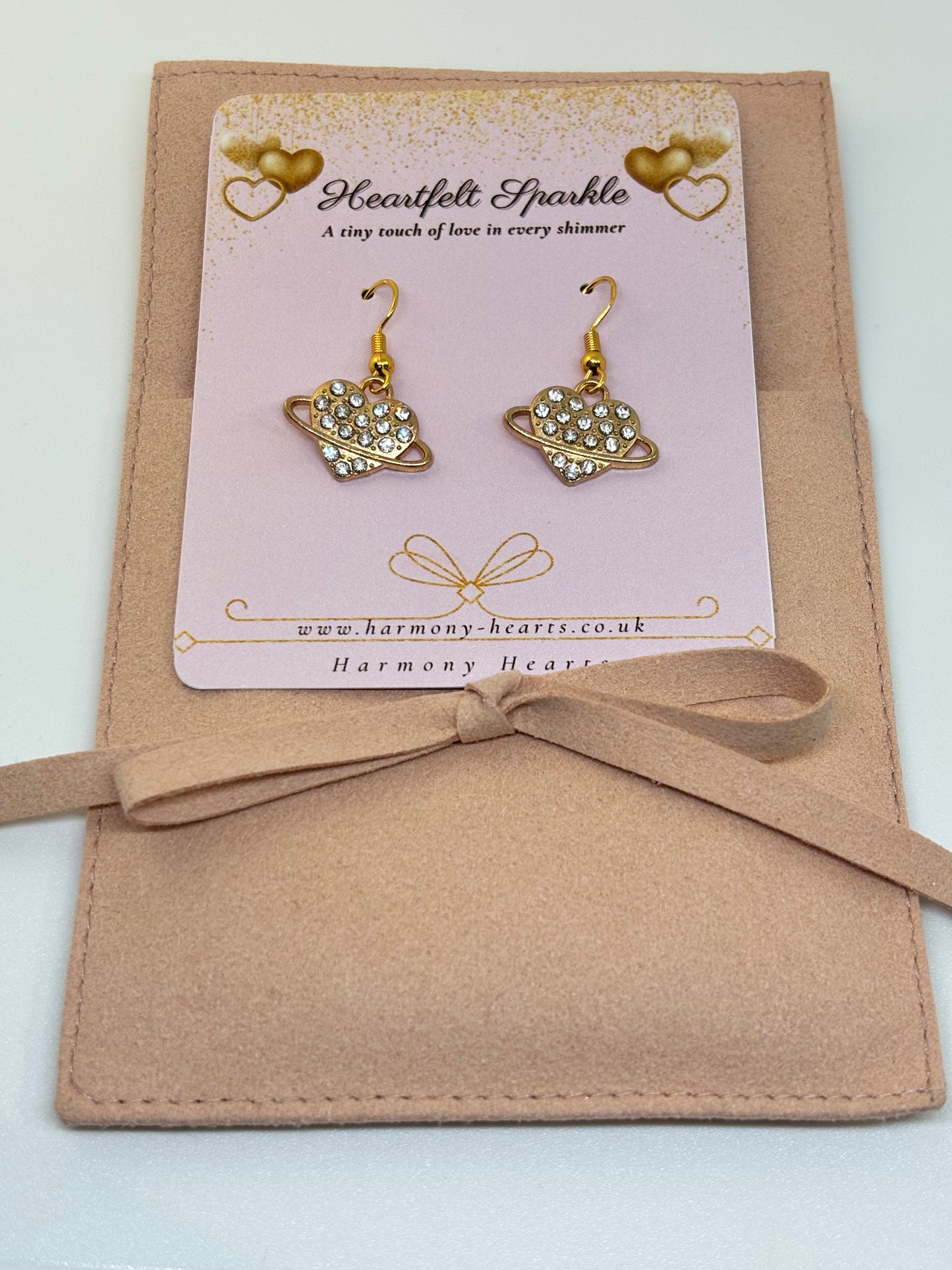 Heart-shaped earrings on a 'Heartfelt Sparkle' card with a bow on a beige background