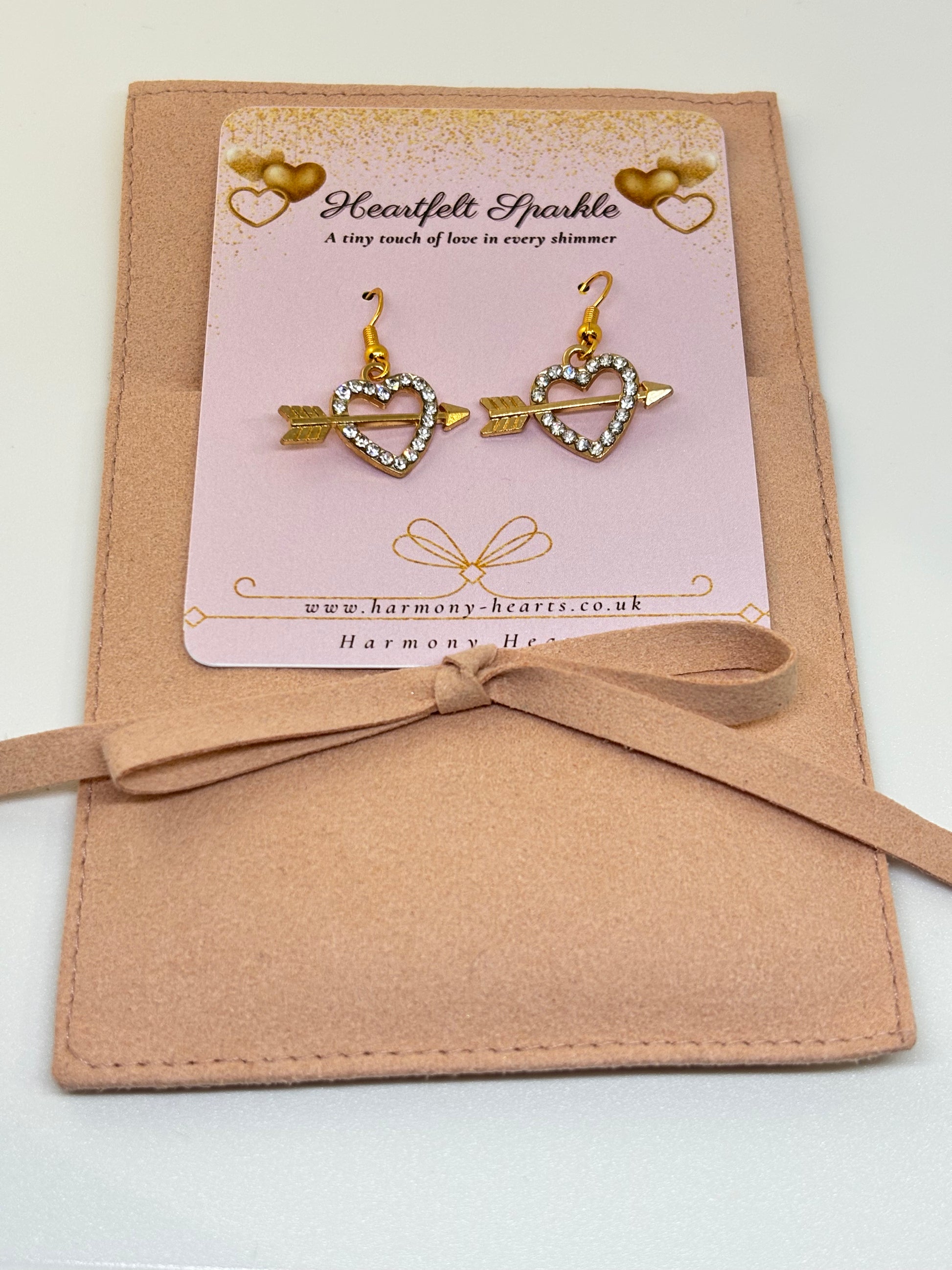 Heart-shaped earrings on a pink card with 'Harmony Hearts' branding, tied with a ribbon.