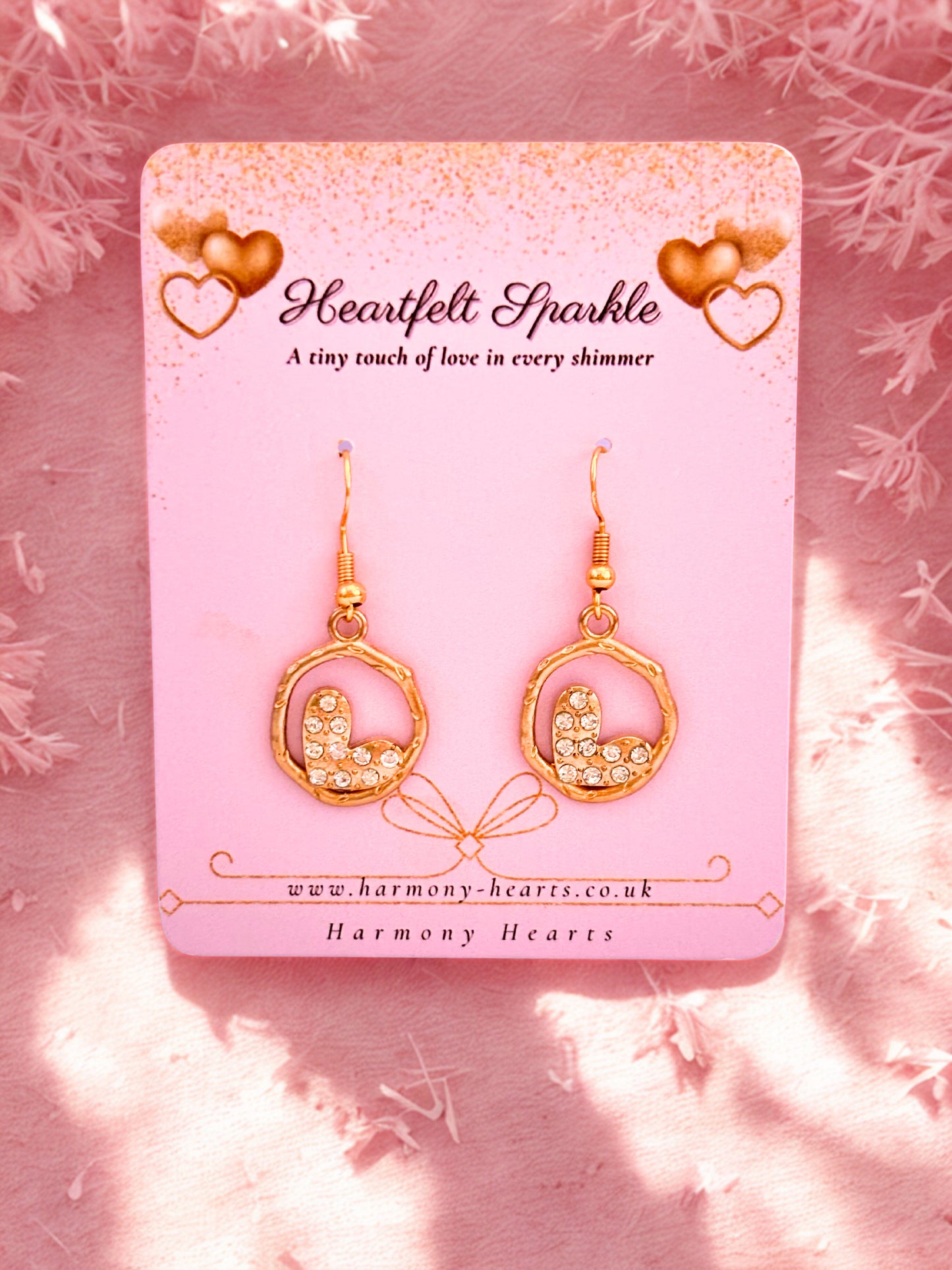 Gold heart-shaped earrings on a pink card with 'Heartfelt Sparkle' branding.