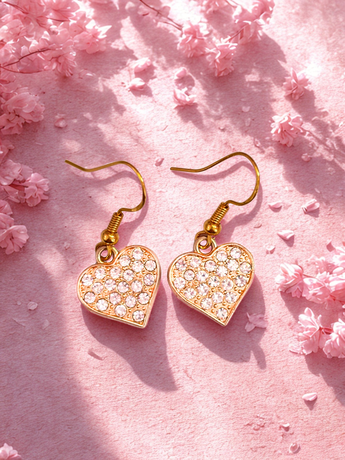Heart-shaped earrings with rhinestones on a pink floral background